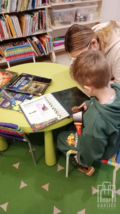 Biblioteka Gorlice, Ferie w bibliotece Uczestnik zajęc ogląda prezentowane książki